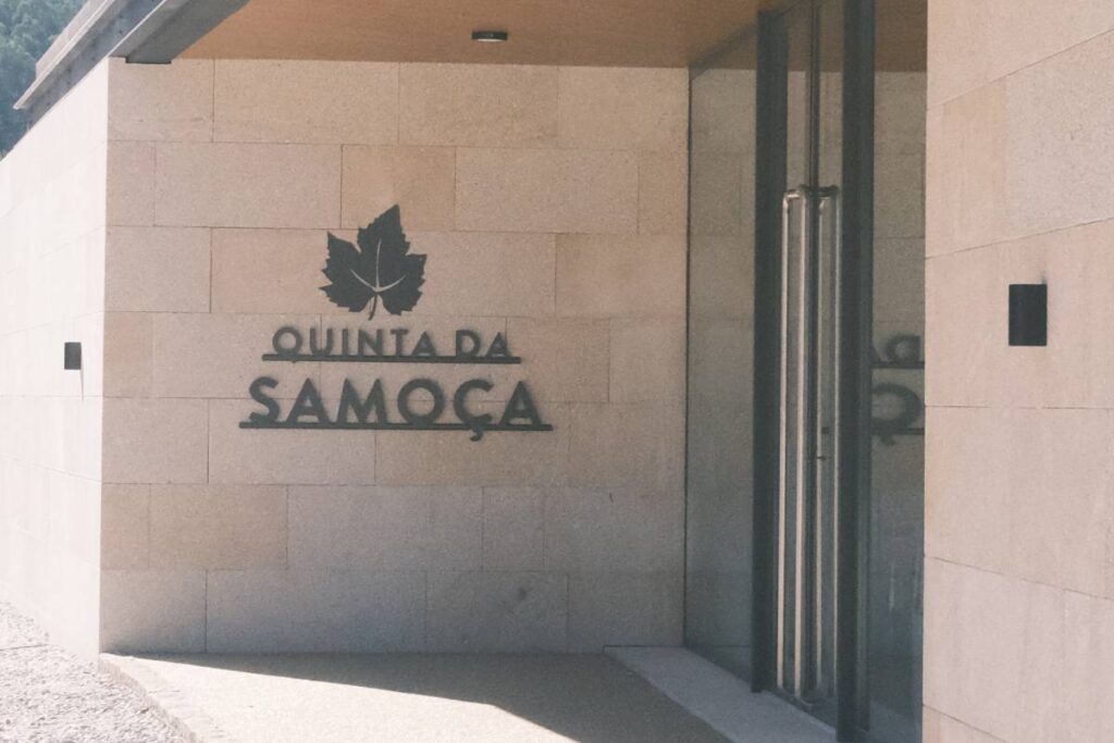 Entrada da Quinta da Samoça, edifício de arquitetura moderna em pedra com logótipo gravado na fachada.